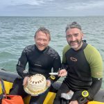 Two divers on a dive boat with a cake